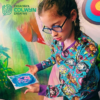 A child showing her painted picture using colours such as pink and blue