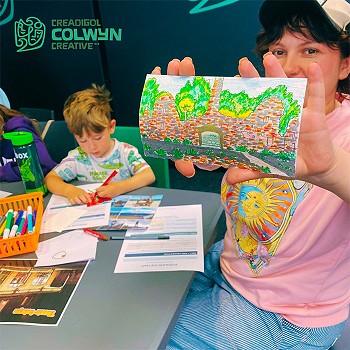 A child showing a picture she has drawn and coloured using a variety of colours